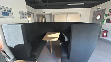 Ensemble de mobilier de réunion composé de banquettes à haut dossier formant un espace semi-fermé avec table centrale