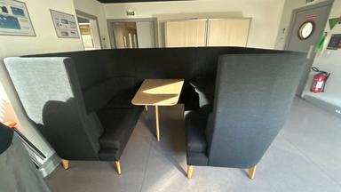 Ensemble de mobilier de réunion composé de banquettes à haut dossier formant un espace semi-fermé avec table centrale